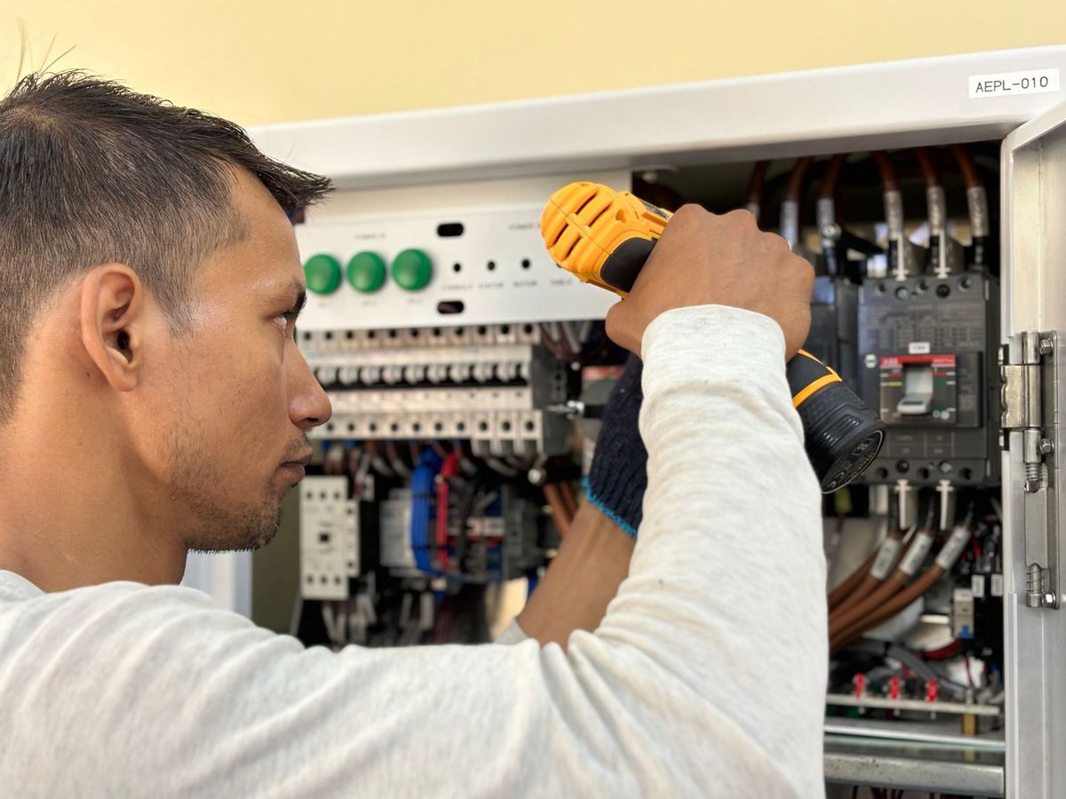 Electrician working inside an open breaker panel