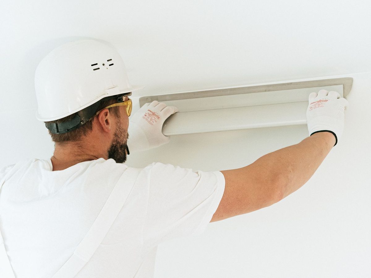Electrician in a hard hat installing a wall fixture