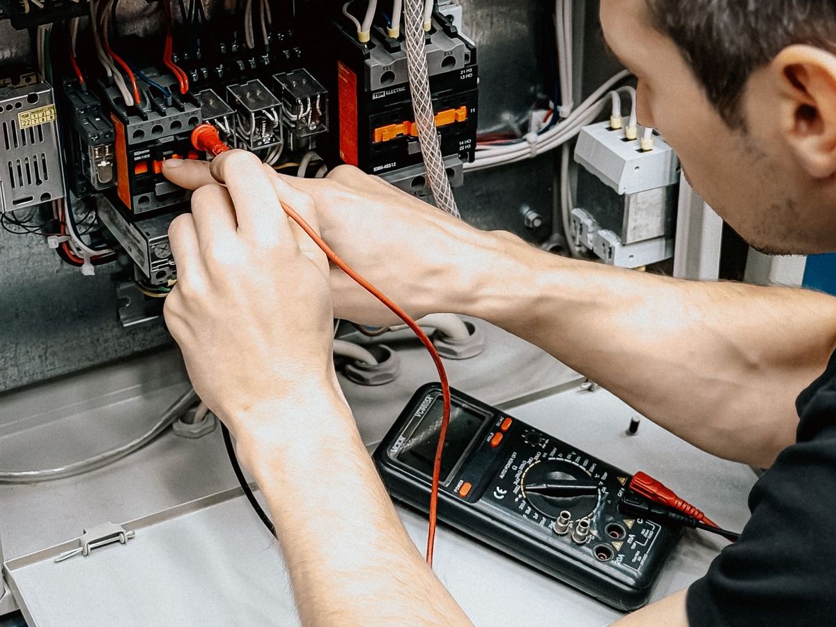Electrician testing an open panel with a multimeter