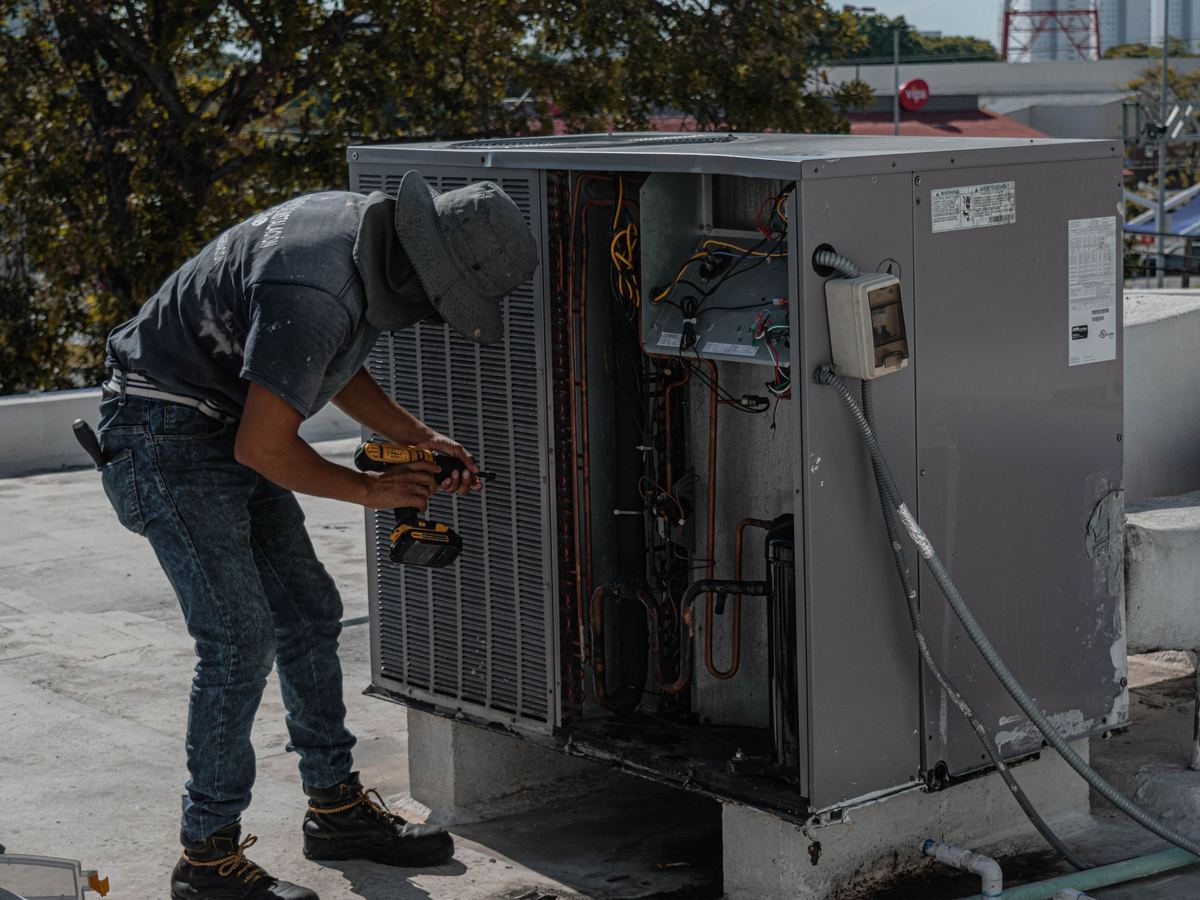 Technician repairing a rooftop air conditioning unit