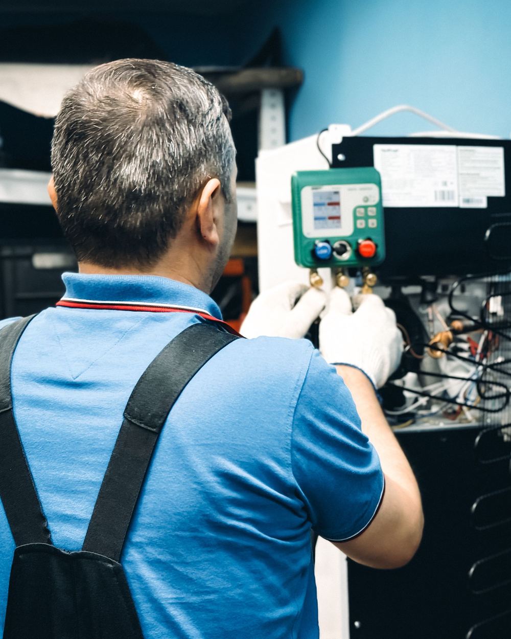 HVAC technician checking a control board with a digital gauge