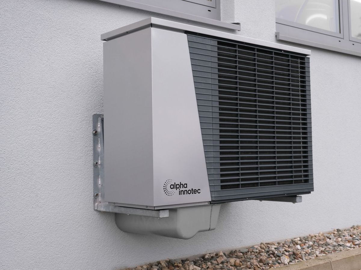 Wall-mounted outdoor heat pump unit on a white building