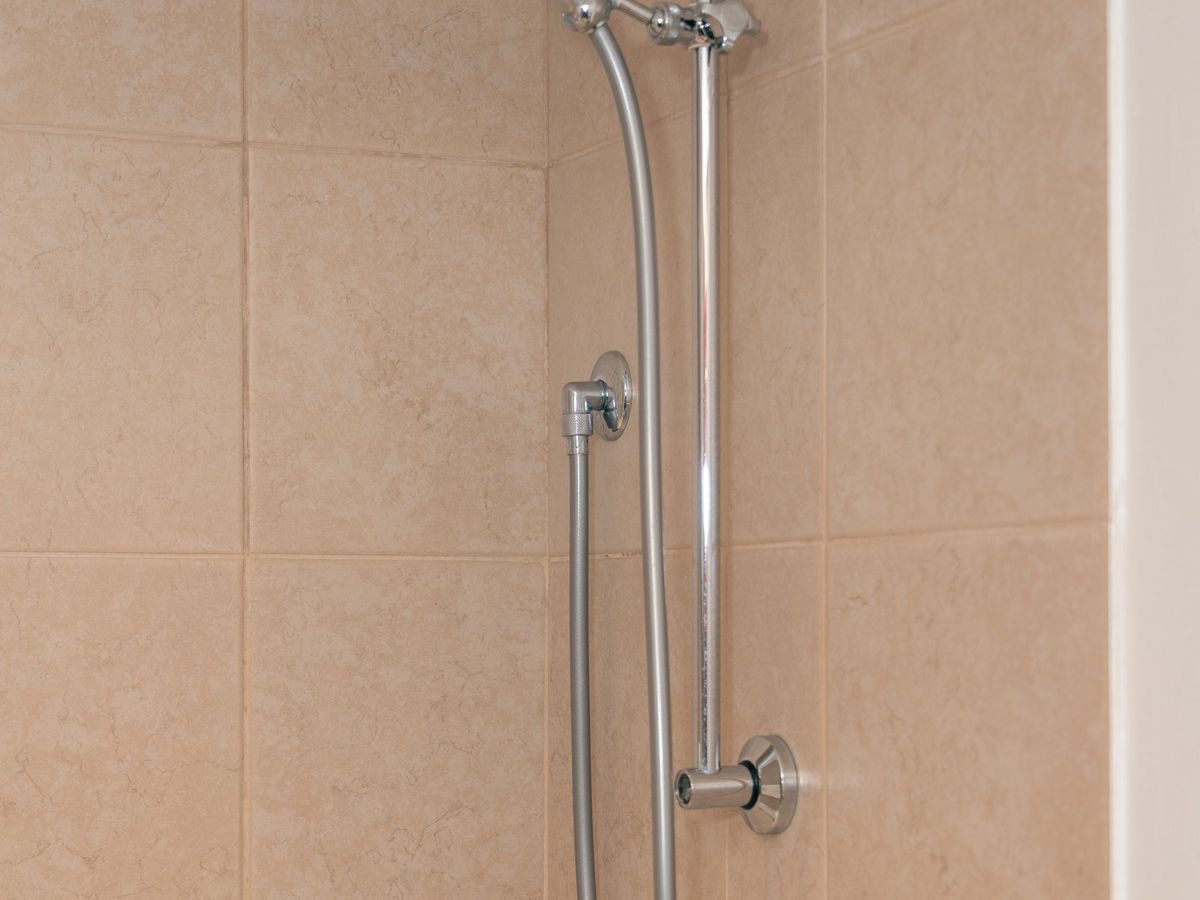 Chrome shower fixture in a beige tiled bathroom