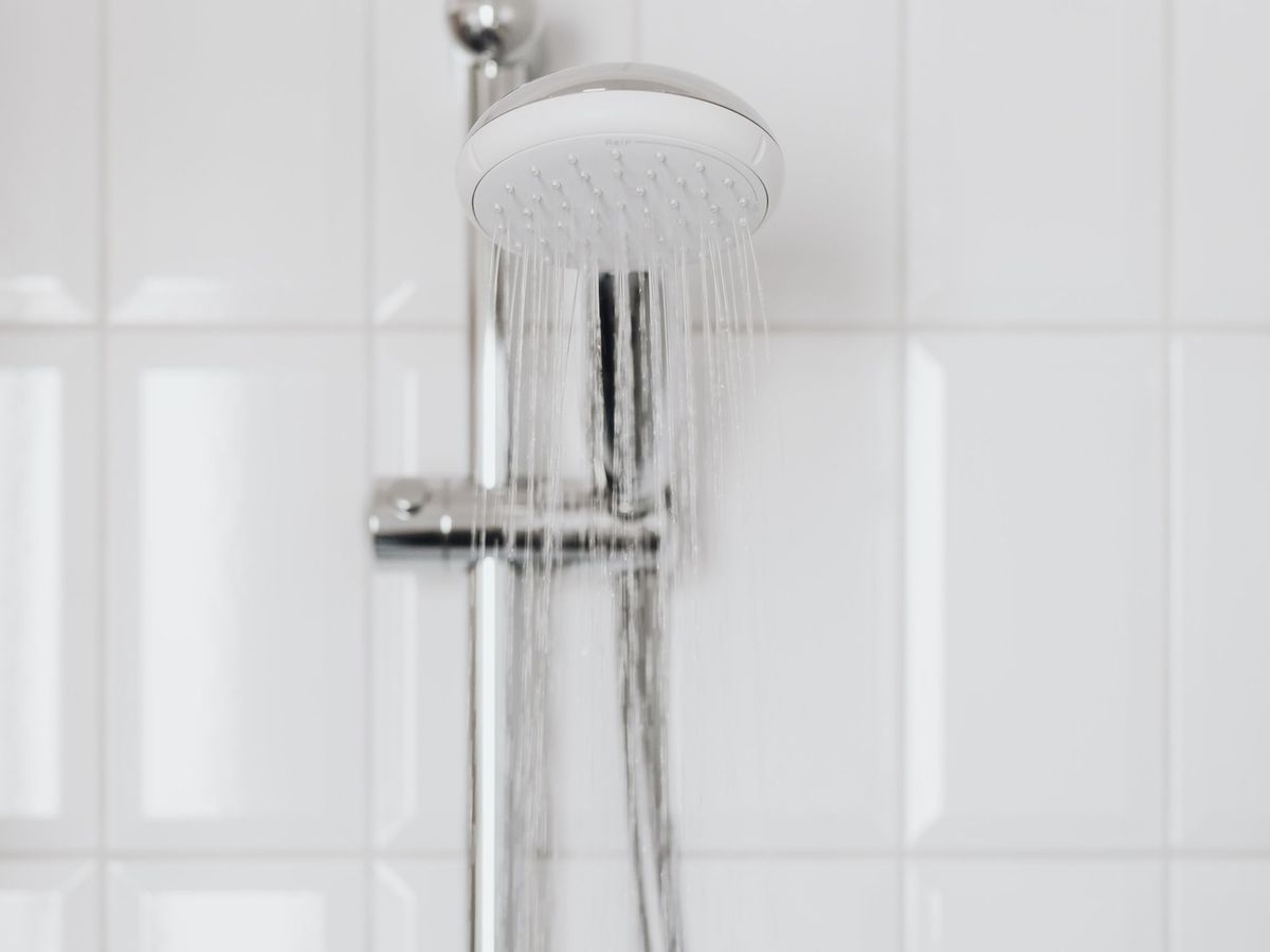 New chrome handheld shower head on white tile
