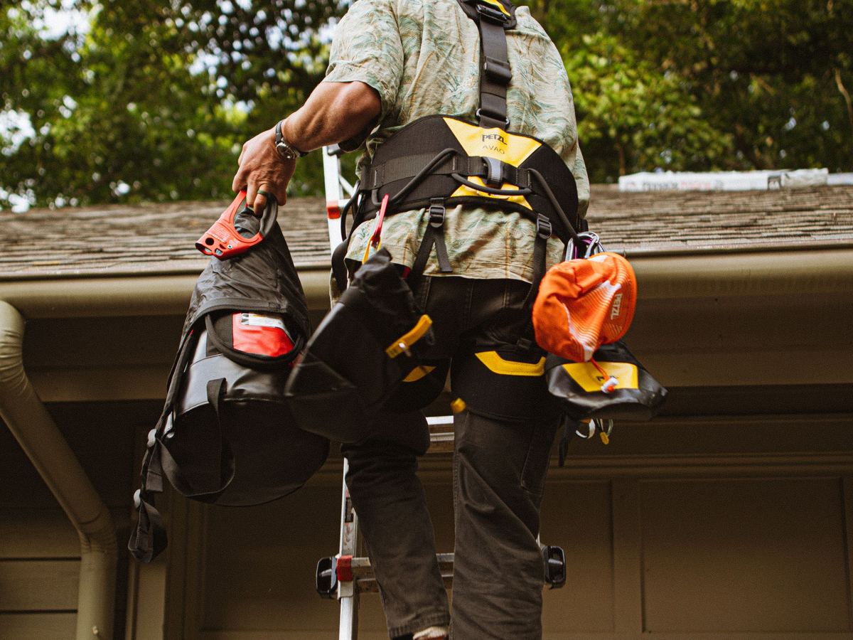 Roofer climbing a ladder to inspect a home's roof