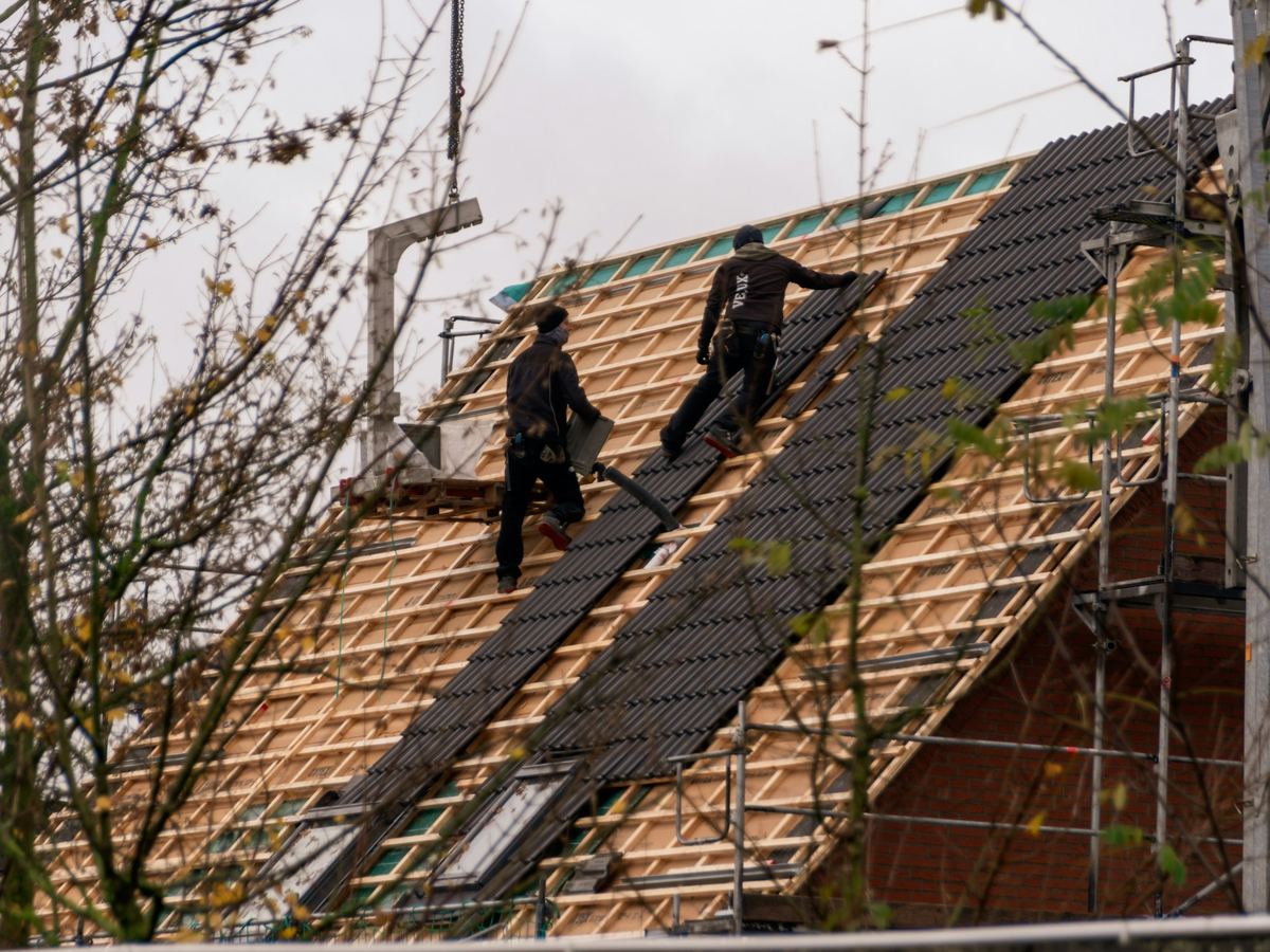 Crew laying new shingles on a steep residential roof